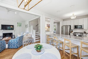 Une cuisine moderne avec des meubles blancs, des appareils en acier inoxydable et un coin repas comprenant une table ronde et des chaises.