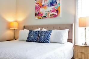 Une chambre d’hôtel avec un lit, deux oreillers, une table de chevet, une lampe et un tableau au mur.