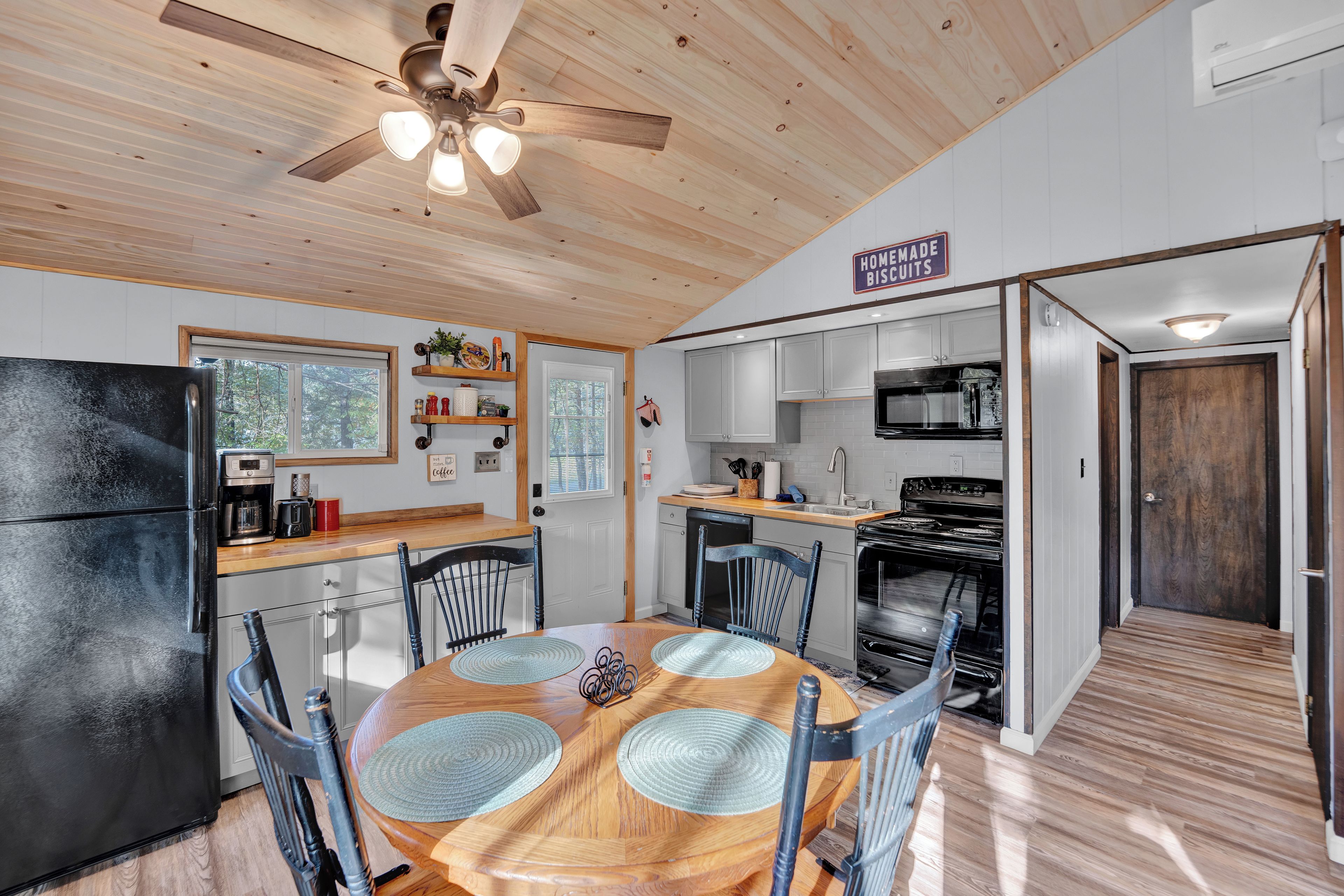 A compact kitchen with a dining area, wooden ceiling, and a sign indicating homemade biscuits.