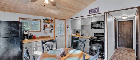 A compact kitchen with a dining area, wooden ceiling, and a sign indicating homemade biscuits.