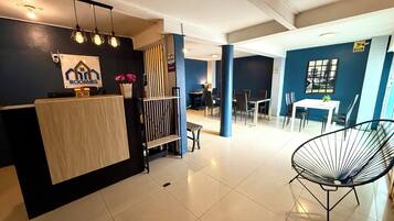 A modern interior with a reception desk, seating area, and dining space.