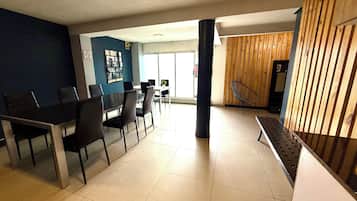 A modern dining area with a black table and chairs, a blue accent wall, and a wooden partition.