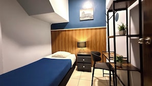 A bedroom with a bed, a desk, a chair, a wardrobe, and a wall-mounted shelf with a plant. - Hostel R&A (Mexico City)
