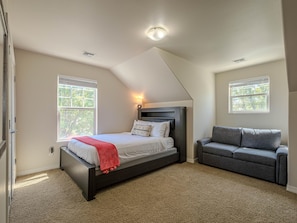 A bedroom with a bed, a gray sofa, and two windows. - Base Camp: Downtown Charm Dogs Welcome! (Fruita)
