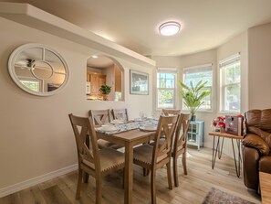 A dining area with a wooden table and chairs, a mirror, and a view of the kitchen. - Base Camp: Downtown Charm Dogs Welcome! (Fruita)