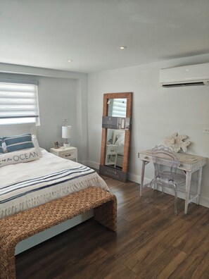 Un dormitorio con cama, mesita de noche, lámpara, espejo y escritorio con silla.