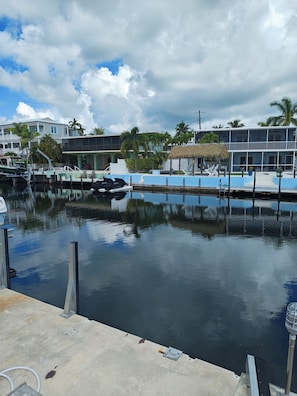 A marina with docked boats, a thatched-roof structure, and a building with a balcony overlooking the water. - Coastal 1 Bedroom Unit with 40 foot boat slip (Tavernier)