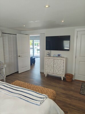 A bedroom with a bed, a television on the wall, a wardrobe, and a door leading to a balcony. - Coastal 1 Bedroom Unit with 40 foot boat slip (Tavernier)
