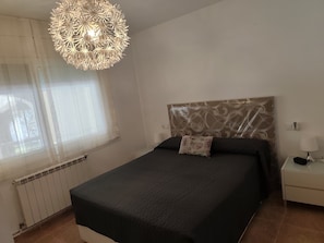 A bedroom with a bed, a nightstand, a lamp, a radiator, and a decorative ceiling light. - Beautiful villa with a garden and pool near the beach (CT)