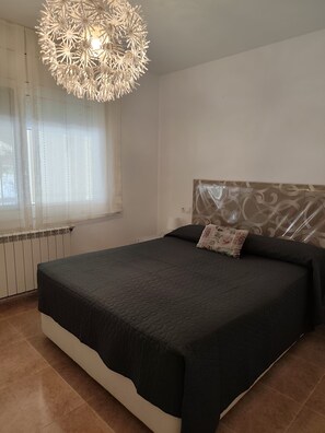 A bedroom with a large bed, a decorative ceiling light, a window with sheer curtains, and a radiator. - Beautiful villa with a garden and pool near the beach (CT)