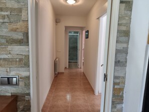A hallway with stone walls, a radiator, and a door leading to a bathroom. - Beautiful villa with a garden and pool near the beach (CT)
