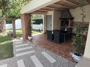 An outdoor patio with a brick floor, a table with chairs, a potted plant, and a grill. - Beautiful villa with a garden and pool near the beach (CT)