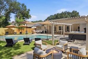 A backyard with a swimming pool, lounge chairs, a fire pit, and a covered patio area. - Resort Getaway: Pool, Hot Tub & Putting Green (San Antonio)
