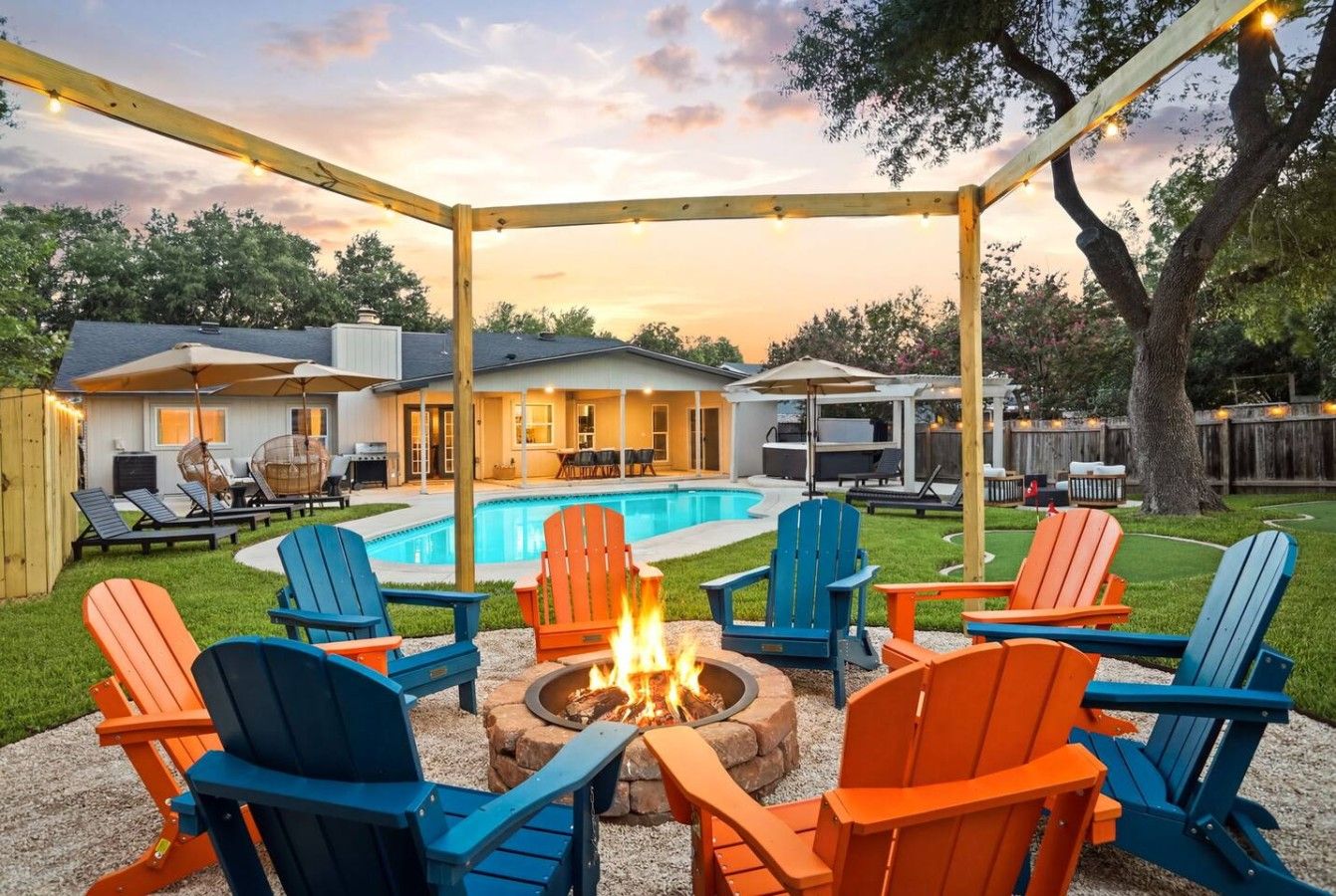 A backyard with a pool, outdoor seating, and a fire pit.