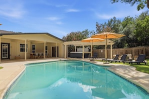 A backyard with a swimming pool, patio furniture, and a covered seating area. - Resort Getaway: Pool, Hot Tub & Putting Green (San Antonio)