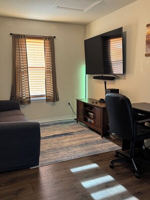 A room with a bed, a desk with a chair, a television, and a window with curtains. - Beautiful 3-bedroom home with AC in tranquil Navarre. 1.5 miles to Navarre Beach (Navarre)