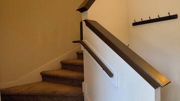 A carpeted staircase with a handrail and wall-mounted light fixtures.