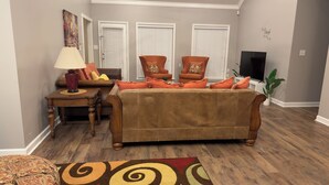 A living room with a brown sofa, two armchairs, a coffee table, and a TV. - Fantastic Family-Friendly 4-BR house with AC  on 3 acres in peaceful WhiteHall. (White Hall)