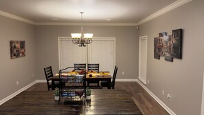 Ein Esszimmer mit Holztisch, Stühlen, einer Chandelierleuchtre und Kunstwerken an den Wänden.