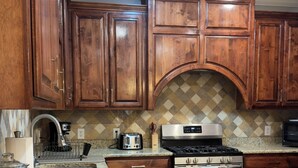 A kitchen with wooden cabinets, a granite countertop, stainless steel appliances, and a patterned backsplash. - Fantastic Family-Friendly 4-BR house with AC  on 3 acres in peaceful WhiteHall. (White Hall)