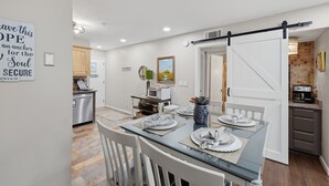 A modern kitchen with a dining area, featuring a glass table, white chairs, and a kitchen counter with appliances. - Steps to beach & pools  Cozy 2-bedroom 2 bath condo in Hilton Head Island (Hilton Head Island)