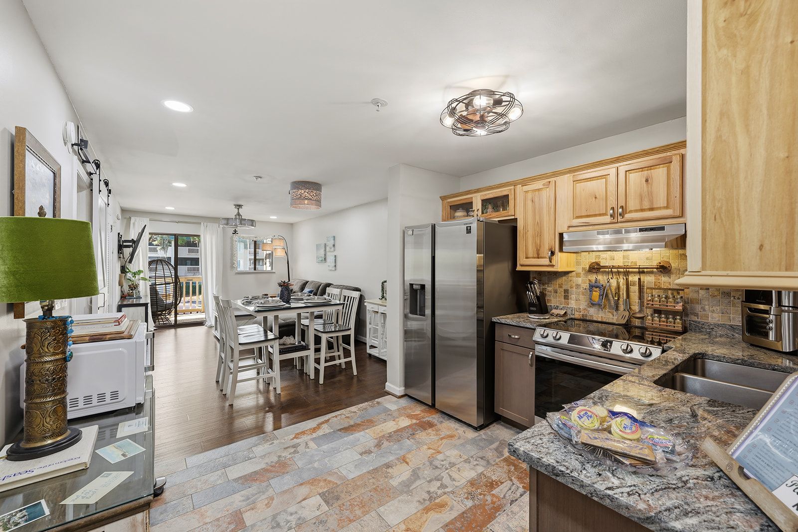 A modern kitchen with stainless steel appliances, wooden cabinets, and a granite countertop.