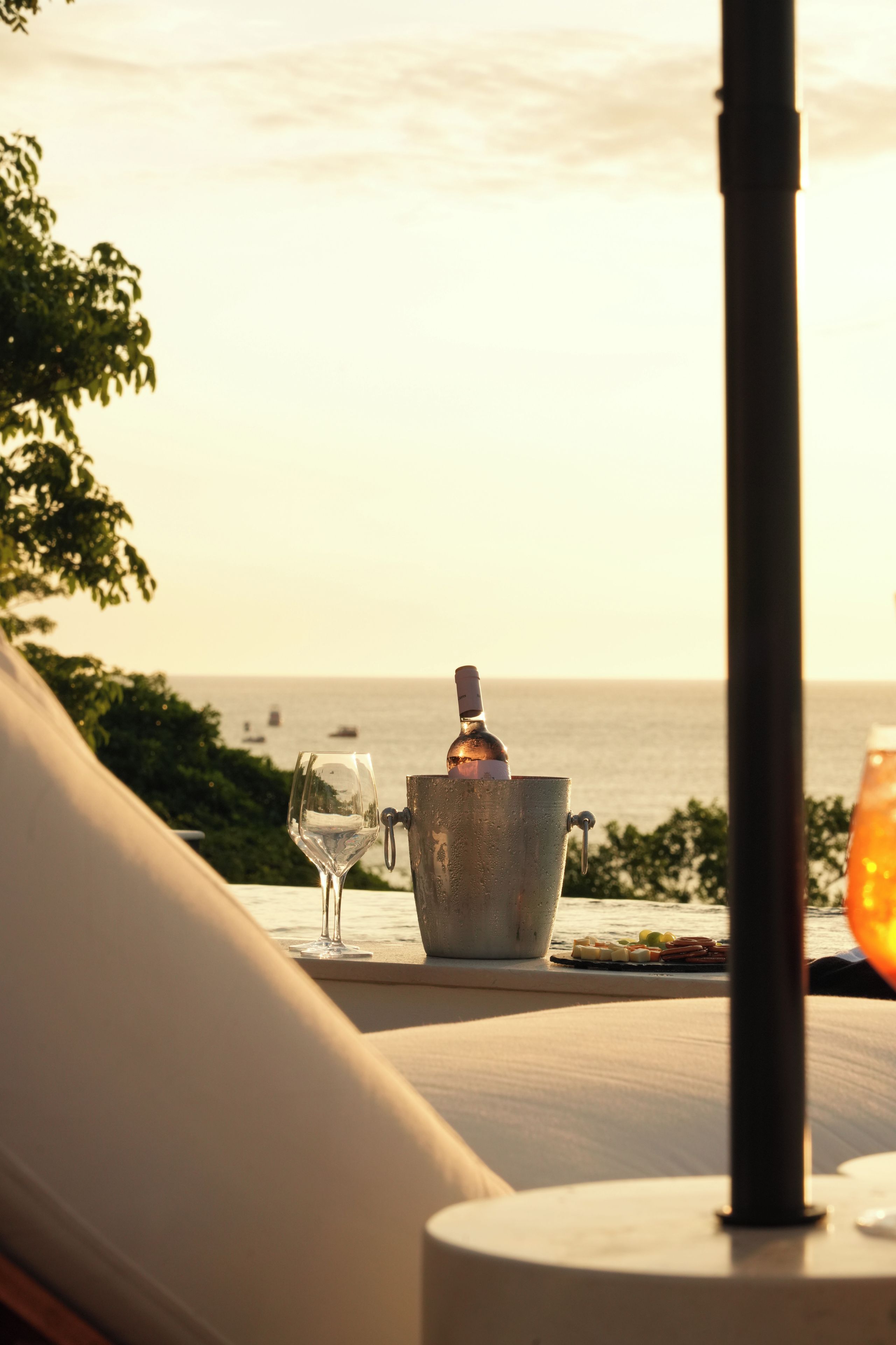 A table with a wine bottle, a glass, and a candle, overlooking a body of water.