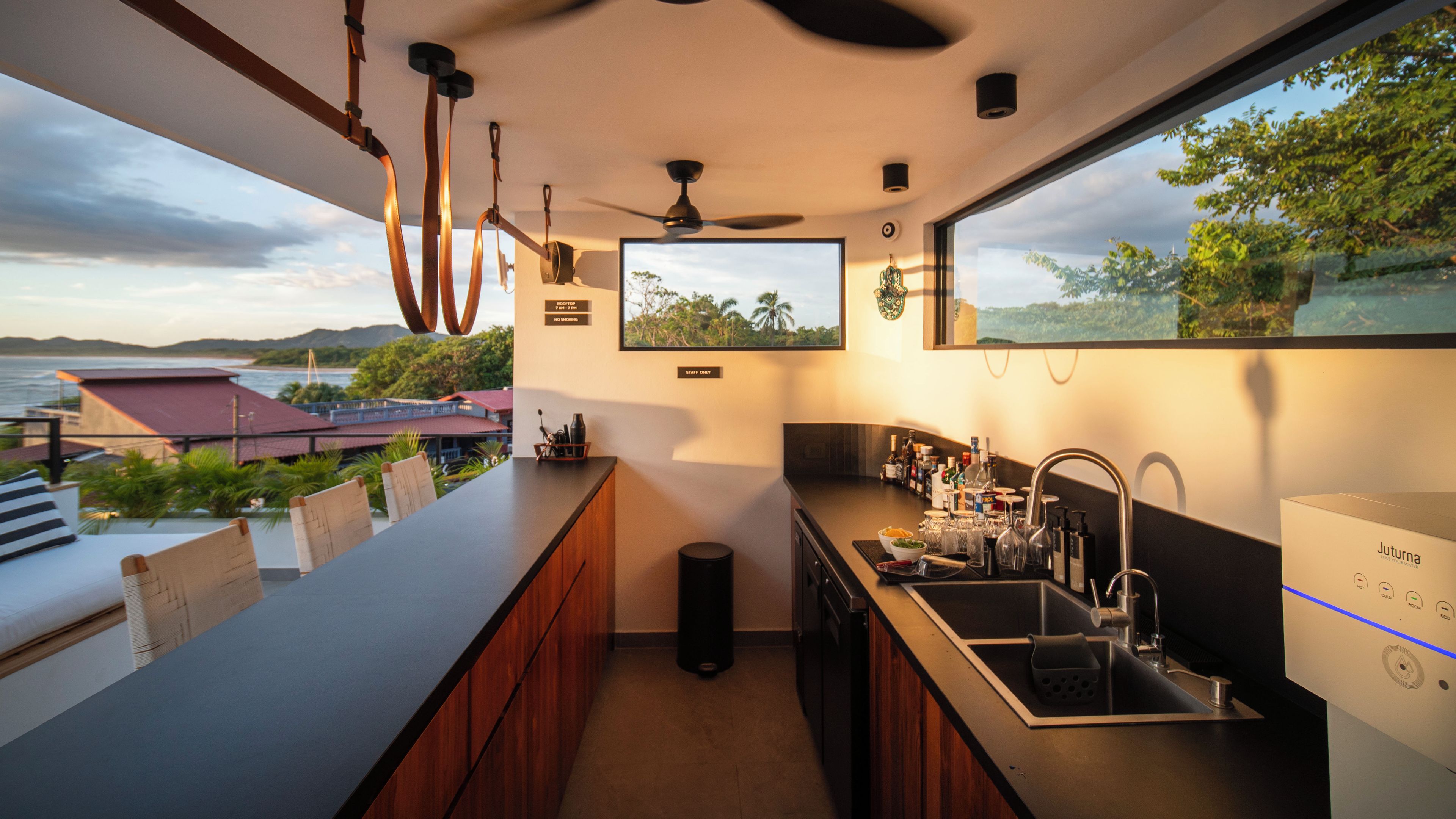 Una cocina moderna con un ventanal amplio, un ventilador de techo y vista al mar.