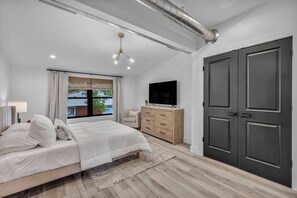 Un dormitorio moderno con cama, cómoda, televisor y armario.