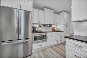 Una cocina moderna con armarios blancos, electrodomésticos de acero inoxidable y piso de madera.