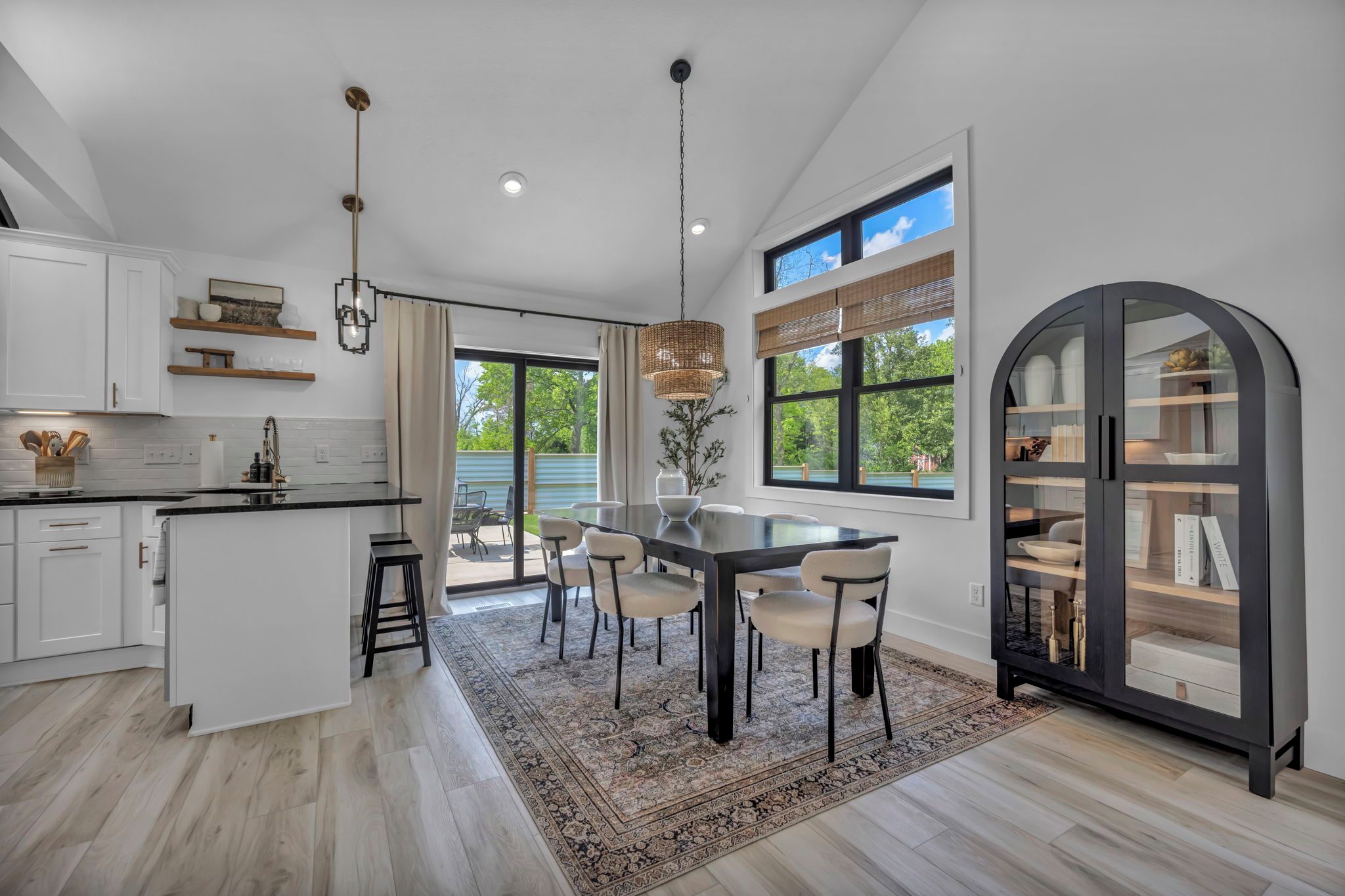 Une cuisine moderne dotée d’un îlot central, d’un coin repas avec des chaises et d’une grande fenêtre donnant sur un paysage verdoyant.