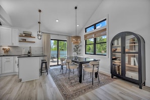 Une cuisine moderne dotée d’un îlot central, d’un coin repas avec des chaises et d’une grande fenêtre donnant sur un paysage verdoyant.