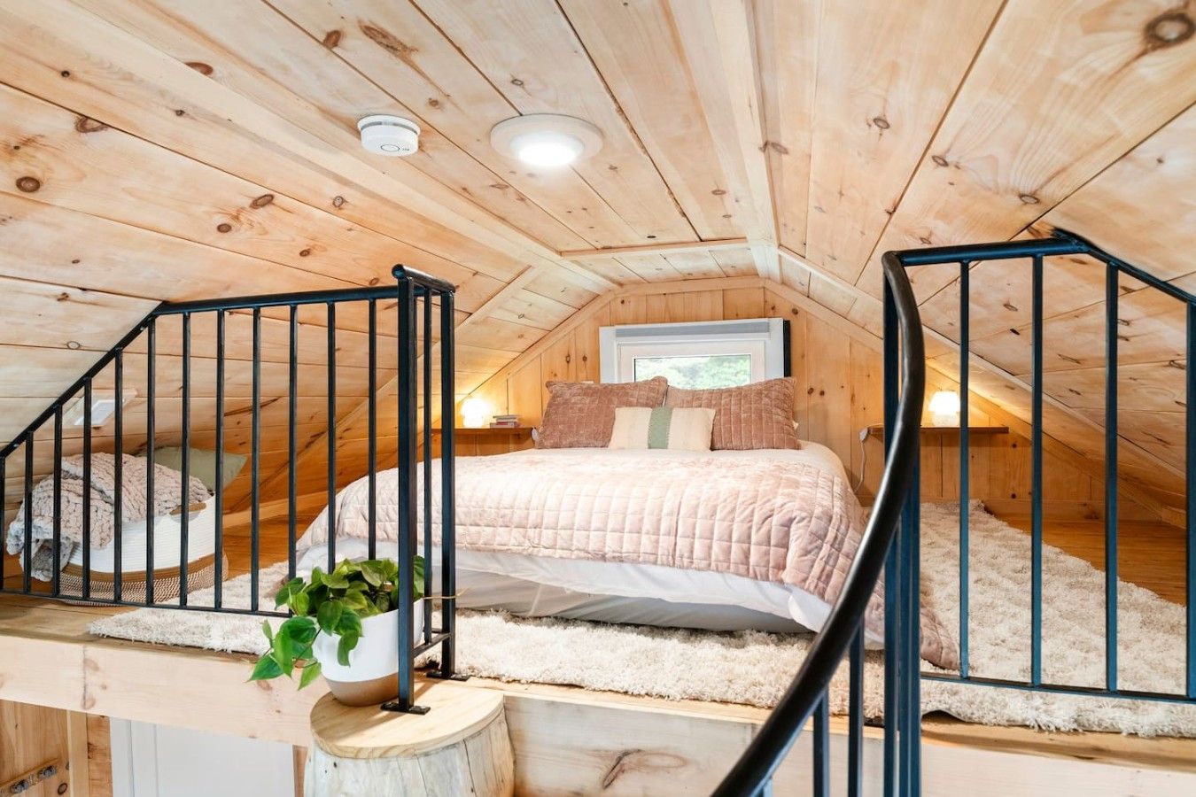 Ein gemütliches Schlafzimmer im Dachgeschoss mit einem Bett, einer Topfpflanze und einer Treppe.