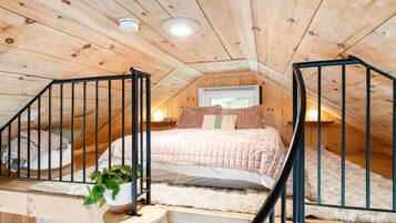 Een knus slaapkamer op zolder met een bed, een potplant en een trap.