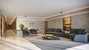 Een moderne woonkamer met een zithoek, twee fauteuils, een salontafel en een groot abstract kunstwerk aan de muur.