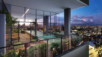 A modern apartment with a glass balcony, a small pool, and a city view.