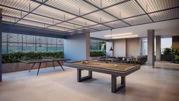 A modern indoor recreational area with a pool table, ping pong table, and seating area.