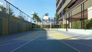 Een buitentoegen basketbalveld met een korf, omringd door een hek van gaas en een gebouw met meerdere ramen.
