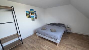 Une chambre avec un lit superposé, une table de chevet, une lampe et une étagère fixée au mur.