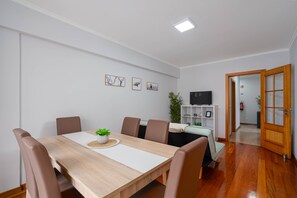 A dining area with a wooden table, six chairs, and a small plant on the table. - Simon's Apartment by Galmi (Machico)
