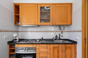 A kitchen with wooden cabinets, a stainless steel stove, and a sink. - Simon's Apartment by Galmi (Machico)