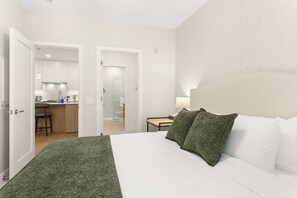 A hotel room with a bed, a nightstand, a lamp, and a view of the bathroom and kitchen. - Revelhaus (Revelstoke)