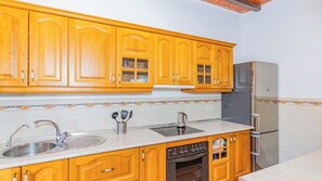 A kitchen with wooden cabinets, a stainless steel sink, a dishwasher, and a refrigerator. - Finca Borjita Alhaurín el Grande by Ruralidays (Málaga)