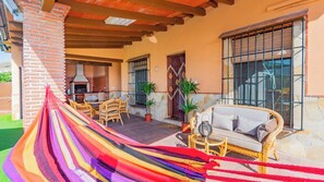 A covered outdoor area with a hammock, wicker furniture, and a stone wall. - Finca Borjita Alhaurín el Grande by Ruralidays (Málaga)