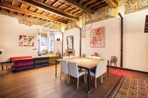 A dining area with a wooden table and chairs, a bench, and a patterned rug. - PoVenti5 | Art House Torino city center · PoVenti5 | Casa d'arte Torino centro (Torino)