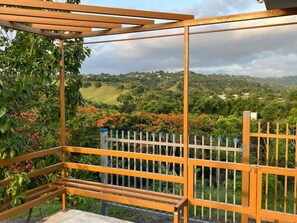 A wooden pergola structure with a view of a green landscape. - Beautiful 3-bedroom house with ocean view and amazing sunsets in charming Rincon (Rincon)