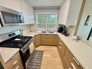 A compact kitchen with a microwave, stove, and sink. - Beautiful 3-bedroom house with ocean view and amazing sunsets in charming Rincon (Rincon)