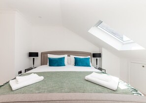 Ein Hotelzimmer mit einem Bett, zwei Nachttischen, einem Oberlicht und einer Tür.