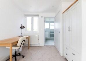 Ein Zimmer mit Holzschreibtisch, einem Stuhl, einer Heizung und einem Kleiderschrank.