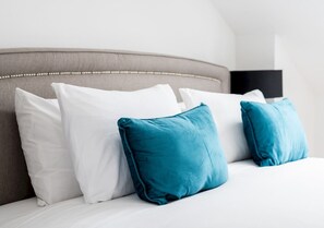 A bed with a headboard, white bedding, and two teal pillows. - Luxury 4BR Kingston | London | Villa | Garden Oasis | Free Parking | Near Train (Kingston upon Thames)